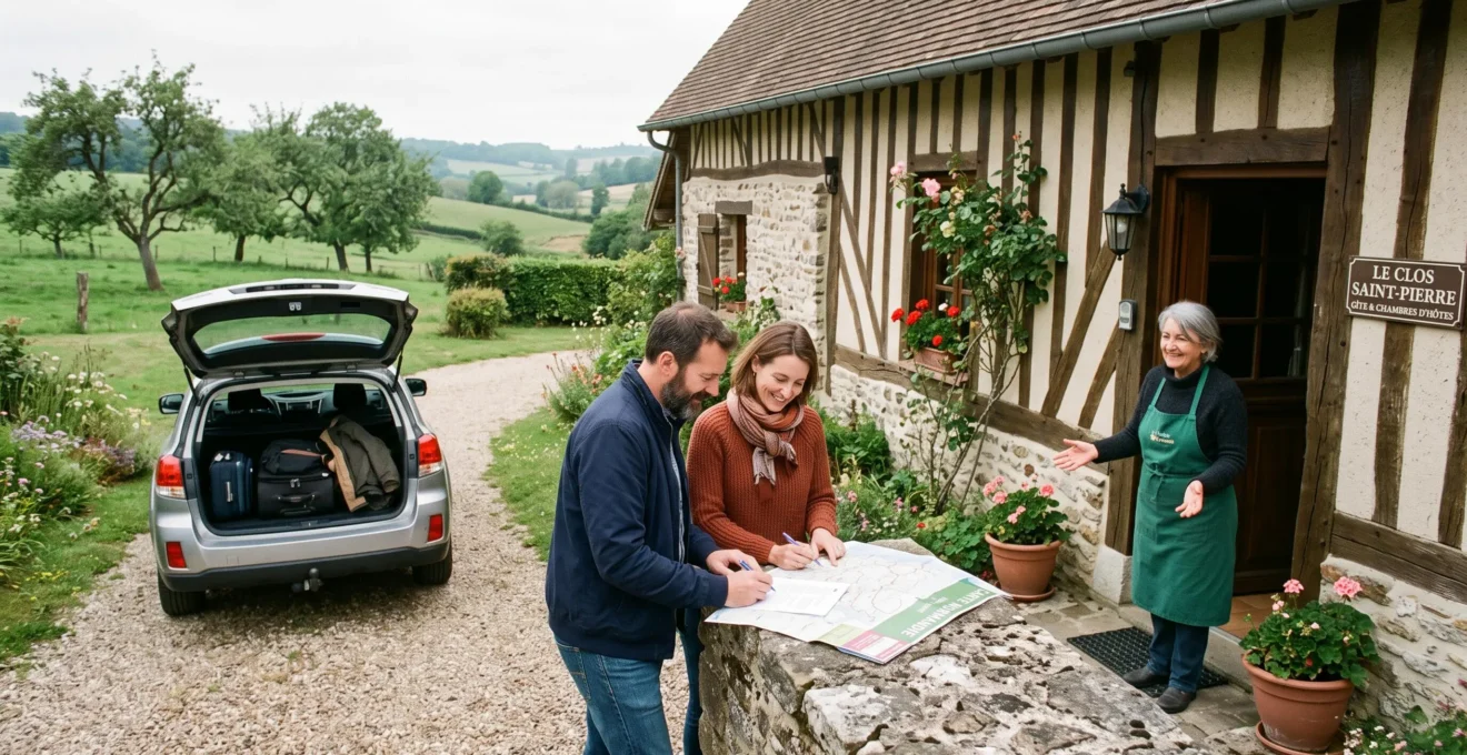 Un couple compare un itinéraire imprimé posé sur un muret en pierre devant une longère normande à colombages tandis que le propriétaire les accueille sur le seuil.