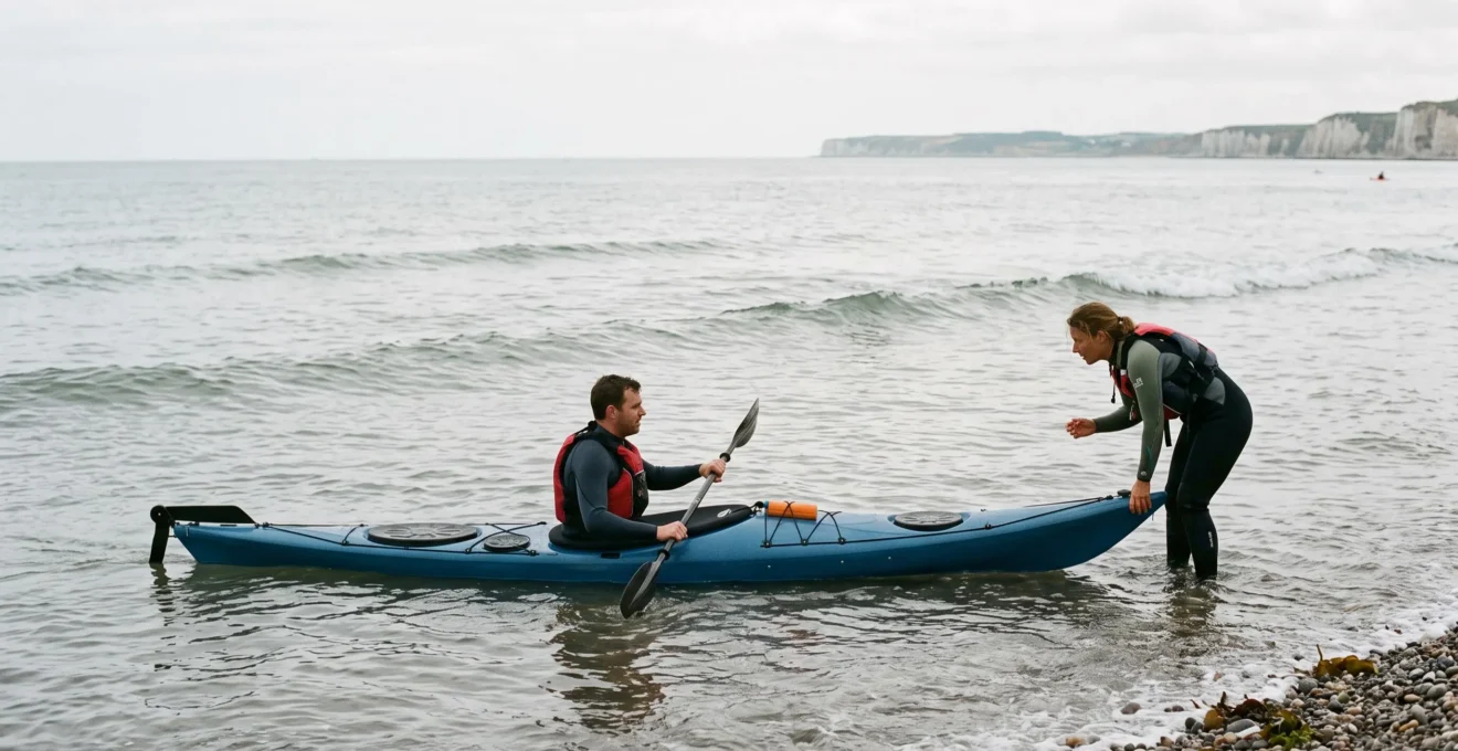 Un kayakiste débutant en combinaison reçoit les instructions d'un guide qui maintient son kayak de mer au bord de la côte normande.