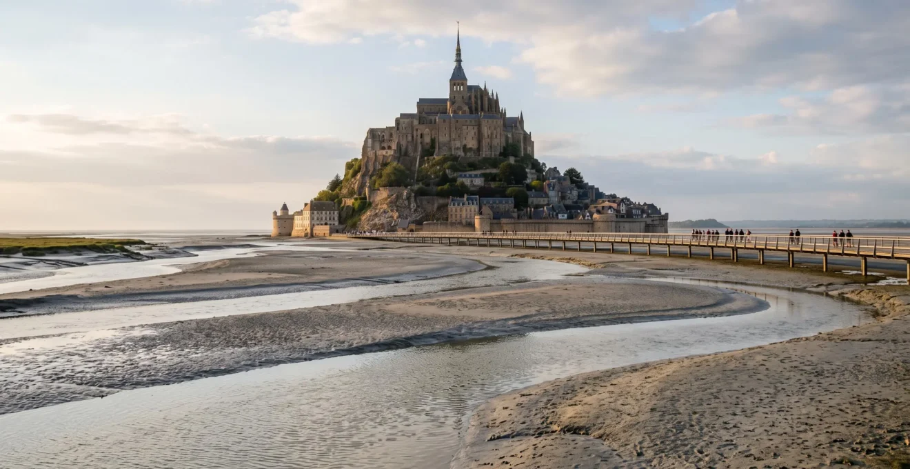 Vue large du Mont-Saint-Michel à marée basse, avec son abbaye médiévale sur le rocher et la baie envasée autour du site classé.