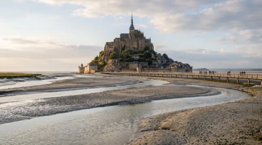 Vue large du Mont-Saint-Michel à marée basse, avec son abbaye médiévale sur le rocher et la baie envasée autour du site classé.
