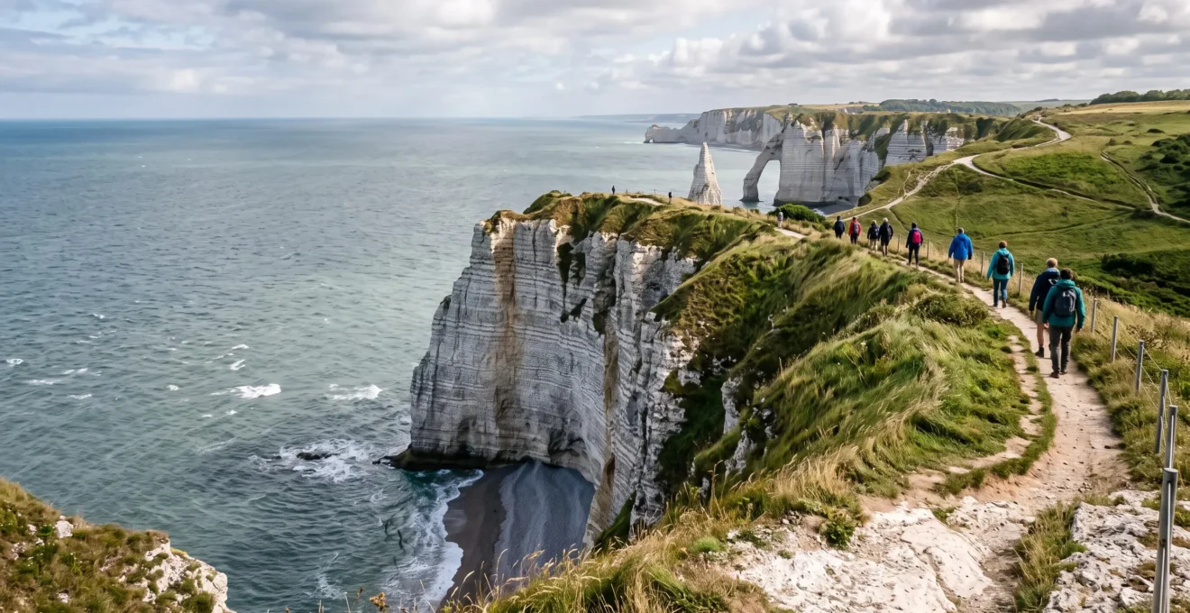 Panorama de la Côte d'Albâtre en Normandie avec de hautes falaises de craie blanche dominant la mer et des promeneurs sur le sentier du plateau.