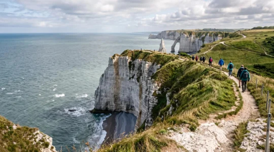 Panorama de la Côte d'Albâtre en Normandie avec de hautes falaises de craie blanche dominant la mer et des promeneurs sur le sentier du plateau.